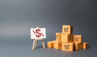 A pile of cardboard boxes and stand with a red down arrow. decline in the production of goods and products, the economic downturn and recession. Falling consumer demand, Falling prices, lower profits photo