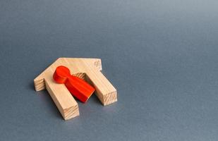 Red figurine of a man and a fallen house on a gray background. Concept of accident or disaster. The consequences of the war, the collapse of the building. Life and property insurance photo