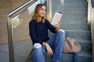 Middle-aged woman reading with her e-book on a coffee break near her office. photo