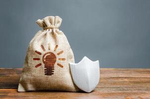 A bag with ideas or patents and a shield. The concept of protection of copyright and patents for inventions. Non-disclosure agreement. trade secrets and industrial espionage. Technology Abduction photo