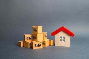A pile of cardboard boxes and a wooden house. Concept of moving to another house or city. Property transportation. Freight shipping, delivery and installation. The beginning of a new stage of life photo