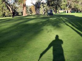 A golfer shadows casted on the fairway photo