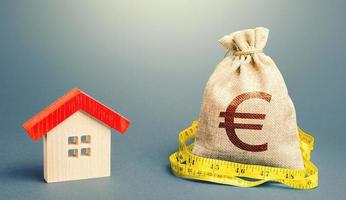 House and a euro money bag. Property real estate valuation. Buying and selling, fair price. Building maintenance. Mortgage loan. Calculation of expenses for purchase, construction and repair. photo