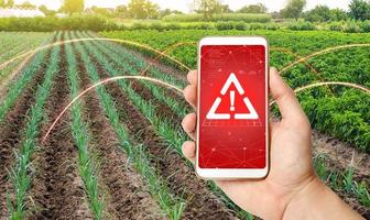 The phone warns of the danger on the farm field. Monitoring and analysis of presence of chemicals, heavy metals, pollution, radiation or microplastics in the crop. Health hazard, harmful substances. photo