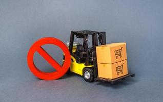 Yellow Forklift truck carries boxex and a red prohibition symbol NO. Embargo trade wars. Restriction on importation production, ban on export of dual-use goods to countries under sanctions photo