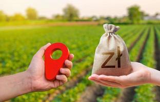 Hands with location pin and polish zloty money bag. Estimation cost of plots. Agriculture agribusiness. Transport and construction industry. Buying and selling land. Land market. photo