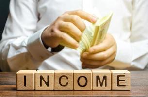 Businessman counting money in hands near inscription income. Successful business investment. Profitable and liquid business, success. Fixation of income and return on investment with interest earnings photo