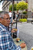elderly street artist, brown latino man, painting pictures on the street, mexico photo
