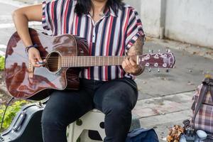 mujer latina tocando guitarra en la calle, joven morena, américa latina foto