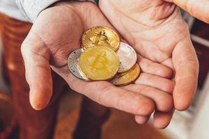 Man hand holding cryptocurrency golden and silver bitcoin coin. Electronic virtual money for web banking and international network payment. Symbol of crypto virtual currency. Mining concept. photo