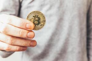 Man hand holding cryptocurrency golden bitcoin coin. Electronic virtual money for web banking and international network payment. Symbol of crypto virtual currency. Mining concept. photo