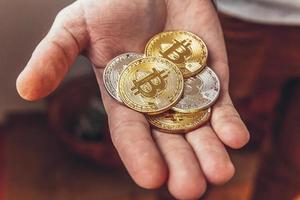 Man hand holding cryptocurrency golden and silver bitcoin coin. Electronic virtual money for web banking and international network payment. Symbol of crypto virtual currency. Mining concept. photo