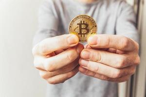 Man hand holding cryptocurrency golden bitcoin coin. Electronic virtual money for web banking and international network payment. Symbol of crypto virtual currency. Mining concept. photo
