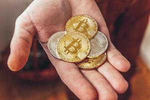 Man hand holding cryptocurrency golden and silver bitcoin coin. Electronic virtual money for web banking and international network payment. Symbol of crypto virtual currency. Mining concept. photo