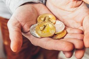 Man hand holding cryptocurrency golden and silver bitcoin coin. Electronic virtual money for web banking and international network payment. Symbol of crypto virtual currency. Mining concept. photo