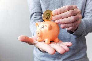 Man hand holding piggy bank with cryptocurrency golden bitcoin coin. Electronic virtual money for web banking and international network payment. Symbol of crypto virtual currency, Mining concept photo