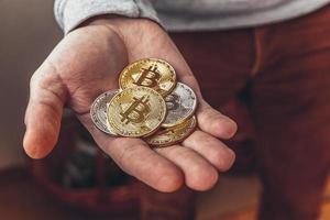 Man hand holding cryptocurrency golden and silver bitcoin coin. Electronic virtual money for web banking and international network payment. Symbol of crypto virtual currency. Mining concept. photo