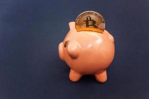 Piggy bank and golden bitcoin coin virtual money on black background. Cryptocurrency and saving concept. Electronic virtual money for web banking and international network payment photo