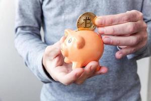 Man hand holding piggy bank with cryptocurrency golden bitcoin coin. Electronic virtual money for web banking and international network payment. Symbol of crypto virtual currency, Mining concept photo