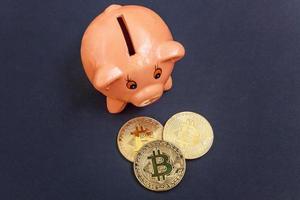 Piggy bank and golden bitcoin coin virtual money on black background. Cryptocurrency and saving concept. Electronic virtual money for web banking and international network payment photo