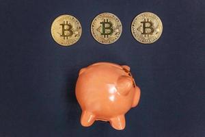 Piggy bank and golden bitcoin coin virtual money on black background. Cryptocurrency and saving concept. Electronic virtual money for web banking and international network payment photo