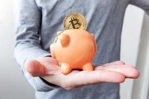 Man hand holding piggy bank with cryptocurrency golden bitcoin coin. Electronic virtual money for web banking and international network payment. Symbol of crypto virtual currency, Mining concept photo