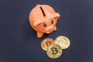 Piggy bank and golden bitcoin coin virtual money on black background. Cryptocurrency and saving concept. Electronic virtual money for web banking and international network payment photo