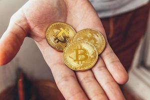 Man hand holding cryptocurrency golden bitcoin coin. Electronic virtual money for web banking and international network payment. Symbol of crypto virtual currency. Mining concept. photo