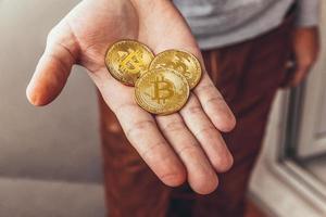 Man hand holding cryptocurrency golden bitcoin coin. Electronic virtual money for web banking and international network payment. Symbol of crypto virtual currency. Mining concept. photo