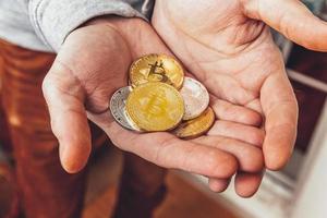 Man hand holding cryptocurrency golden and silver bitcoin coin. Electronic virtual money for web banking and international network payment. Symbol of crypto virtual currency. Mining concept. photo