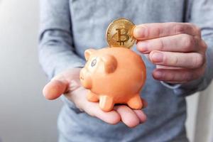 Man hand holding piggy bank with cryptocurrency golden bitcoin coin. Electronic virtual money for web banking and international network payment. Symbol of crypto virtual currency, Mining concept photo