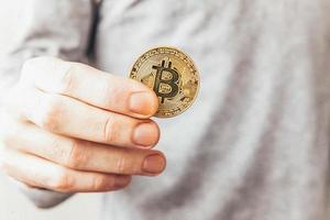 Man hand holding cryptocurrency golden bitcoin coin. Electronic virtual money for web banking and international network payment. Symbol of crypto virtual currency. Mining concept. photo