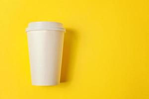 Simply flat lay design paper coffee cup on yellow colorful trendy background. Takeaway drink container. Good morning wake up awake concept. Template of drink mockup. Top view copy space. photo