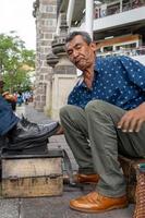 latino mayor, moreno, limpiando y lustrando zapatos, feliz con su profesión mexico foto