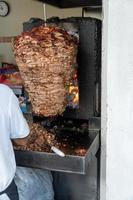 comida mexicana trompo pastor tacos al pastor, carne apilada en salsa con especias foto