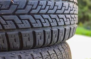 Damaged and worn old black tires on a stack. Damaged and worn old black tires on a stack. Tire tread problems. Solutions concept. Tire tread problems. photo