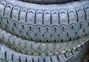 Damaged and worn old black tires on a stack. Damaged and worn old black tires on a stack. Tire tread problems. Solutions concept. Tire tread problems. photo