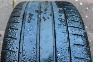 Black big tires in a close up view with water drops. Tire tread problems. photo