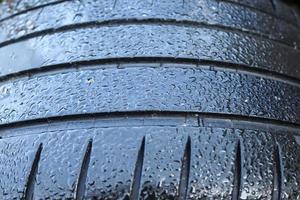 Black big tires in a close up view with water drops. Tire tread problems. photo