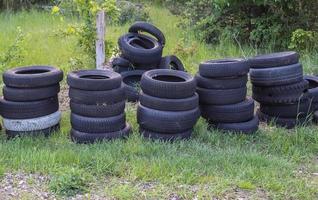 Damaged and worn old black tires on a stack. Damaged and worn old black tires on a stack. Tire tread problems. Solutions concept. Tire tread problems. photo