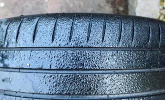 Black big tires in a close up view with water drops. Tire tread problems. photo