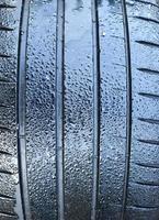 Black big tires in a close up view with water drops. Tire tread problems. photo