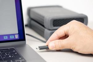 Hand connecting a External hard disk to a modern laptop computer photo