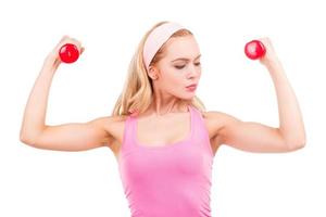 Fit beauty. Beautiful pin-up blond hair woman in pink shirt exercising with dumbbells while standing isolated on white background photo