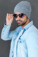 Enjoying his style. Handsome young man in eyewear and headwear posing against grey background photo