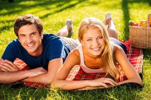 relajarse en el parque juntos. feliz joven pareja amorosa relajándose en el parque juntos mientras están acostados en una manta de picnic foto