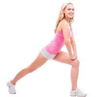 Beauty exercising. Full length of beautiful pin-up blond hair woman in pink shirt doing stretching exercises while standing isolated on white background photo