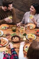 Dining with friends. Top view of four people having dinner together while sitting at the rustic wooden table photo