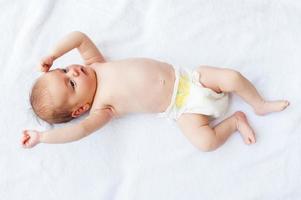 pequeño bebe. vista superior del pequeño bebé en pañales acostado en la cama foto