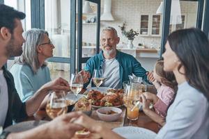 Happy multi-generation family holding hands and praying while having dinner together photo